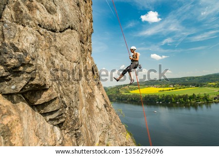 Girl abseiling above Vltava river on beautiful sunny day, Czech republic