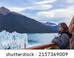 The girl admires the view of the beautiful Perito Moreno glacier and Lake Argentina from the observation deck. El Calafate,  Argentina
