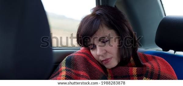The girl after a long road sleeps in the car\
covered with a blanket.