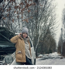 The Girl Is Alone On The Snowy Road. The Car Broke Down, The Hood Is Open. Frustrated Woman Calls On The Phone, Calls Technical Support.