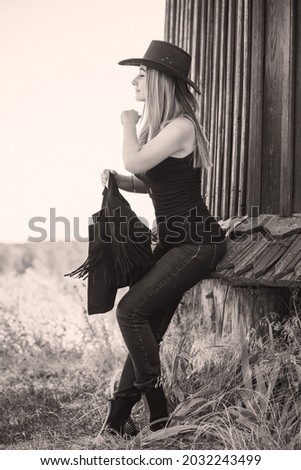 Girl in American country style black boho jacket with a fringe and cowboy hat at nature