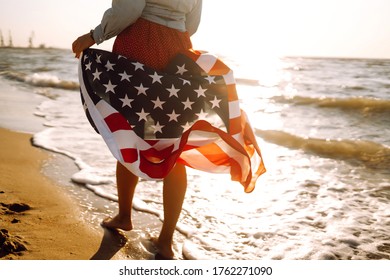 Girl With American Flag On The Beach At Sunset. 4th Of July. Independence Day. Patriotic Holiday.