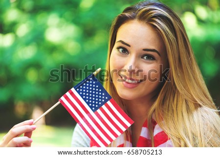 GIrl with an American flag on the fourth of July in her backyard