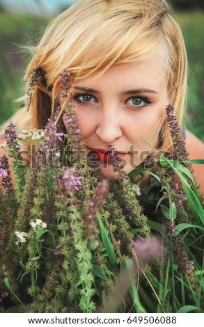 Girl among wild flowers looks at the camera.Enjoyment.Film colors.Vintage style.Hipster girl.