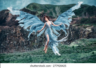  Girl angel with a beautiful wings. As the picture from an old book. She takes off into the sky. Mountains in the background. Early spring. Fashionable toning, picture in the style of fantasy. 