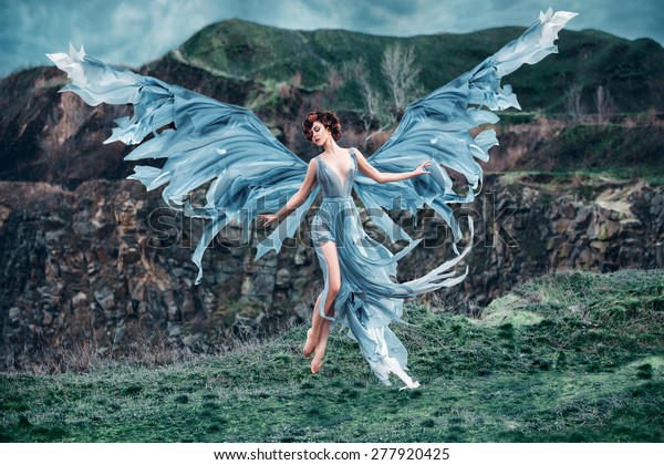 美しい翼を持つ女の子の天使 古い本の絵として 彼女は空に飛び出す 背景に山 早春 ファッショナブルな調子の 空想的なスタイルの絵 の写真素材 今すぐ編集