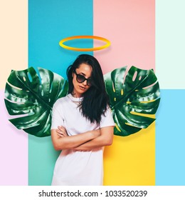 girl angel and wings made palm leaves   halo over her head in white dress colored background