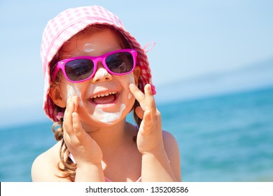Girl anoints her face protective cream on the beach