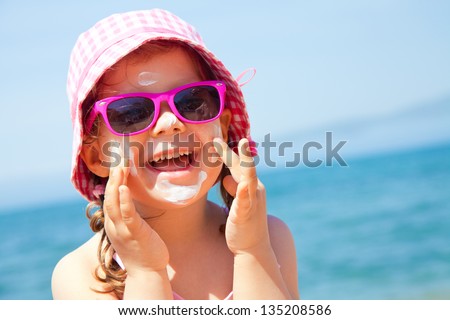 Girl anoints her face protective cream on the beach