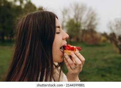 the girl appetizingly eats in the park eats faggots