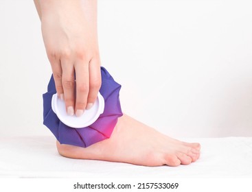 The Girl Applies A Medical Ice Bag To The Ankle Joint To Eliminate Pain And Relieve Swelling. Cold Joint Treatment, Inflammation