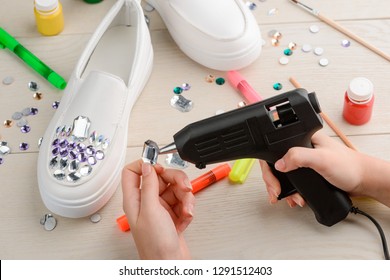 Girl Applying Rhinestones To Her Slip-on Shoes Using Hot Glue Gun. Custom Design Footwear, DIY Concept.