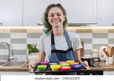 girl in apron in kitchen with tray of preparing raw silicone cupcakes. Home cooking, homemade food - Powered by Shutterstock