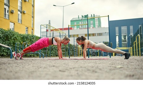 Girl with artificial leg has disability do plank exercise with female friend on fitness mat on sports ground. Caucasian sportswomen wearing sportswear. Healthy lifestyle. Conquering adversity - Powered by Shutterstock