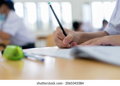 Girl Asian Teen Students Group Concentrate Test Exam Taking Final Examination Desk At Classroom In Thai Student Uniform With Facemask Prevent Covid-19 Health Care For New Normal Education In Thailand