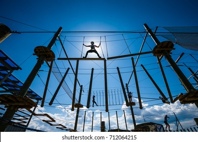 The girl athlete overcoming obstacles in the rope Park. Girl on top, against the sky and the sun - Powered by Shutterstock