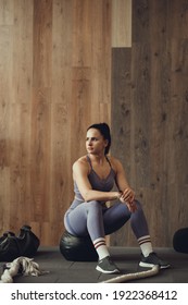 A Girl Athlete With A Pumped-up Booty Squats With A Phyto Ball Near The Wall