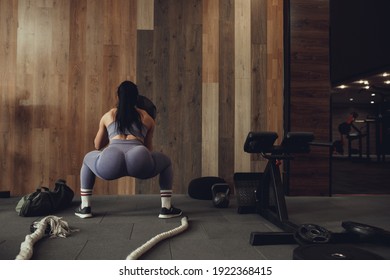 A girl athlete with a pumped-up booty squats with a phyto ball near the wall - Shutterstock ID 1922368415
