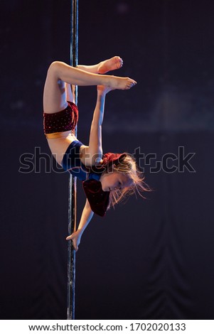 Girl athlete shows an acrobatic performance on a pylon.