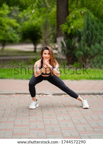 the girl athlete in sports apparel, doing lunges, stretching in the Park. fitness training outdoors. strength exercises, cardio workout.