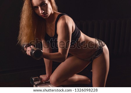 girl athletic lifts dumbbell. exercise for biceps with dumbbells.