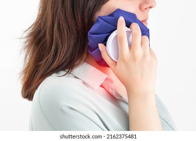 A girl attaches a medical bag with cold to the swelling on her cheek after removing a wisdom tooth. Concept for pain relief and inflammation in dentistry with the help of cold, pulpitis - Shutterstock ID 2162375481