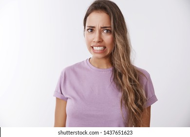 Girl awkward hearing disturbing displeasing story details clenching teeth frowning grimacing aversion, reluctance, showing dislike shock, standing bothered wanna escape uncomfortable situation