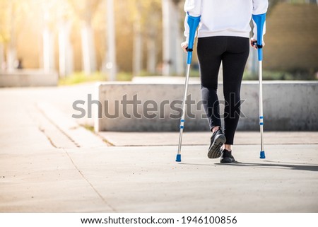 Girl from back with crutches, walking alone. Woman with crutches. Crutches