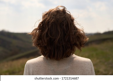 Girl from the back on background of nature landscape and sky pray. Isolated back of woman outdoors, loneliness - Powered by Shutterstock