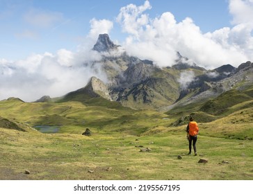 Girl with backpack hiking, Midi dOssau peak in the background in the Pyrenees National Park, France.