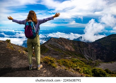 girl with backpack sits on top of volcano irazu in Costa Rica, volcanic landscape of Irazú Volcano National Park, massive volcano in clouds in Costa Rican mountains - Shutterstock ID 2245638791
