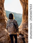 girl with a backpack. A woman with a backpack stands in a cave. The girl explores the cave. Speleologist. Tour of the cave.