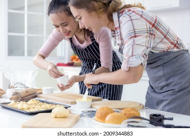 Girl baking cookies, Family Teenage women two of multi ethnic are cooking bread. Bakery in the kitchen at home. Weekend cooking activity for young people. 