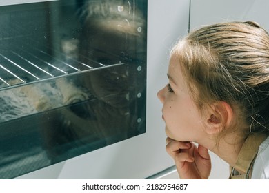 Girl Baking Homemade Cookies And Looking Inside Oven Through Glass