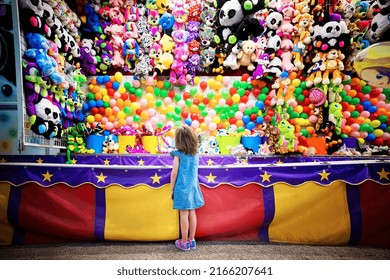 Girl at balloon dart game booth at county fair - Shutterstock ID 2166207641