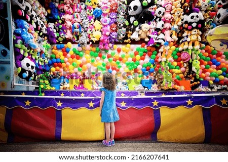 Girl at balloon dart game booth at county fair