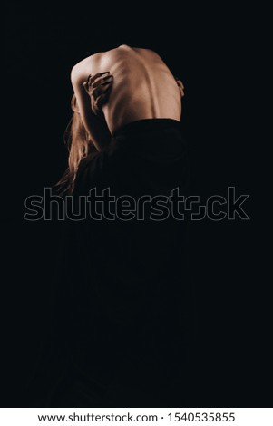 A girl with a bare back, severe thinness and protruding ribs. The concept of anorexia and bulimia, a disease of thin people. The struggle of the evil spirit in a girl, suffering and poverty