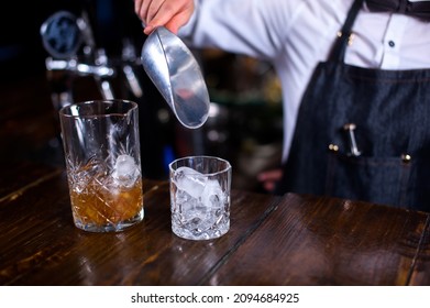 Girl bartender mixes a cocktail behind the bar