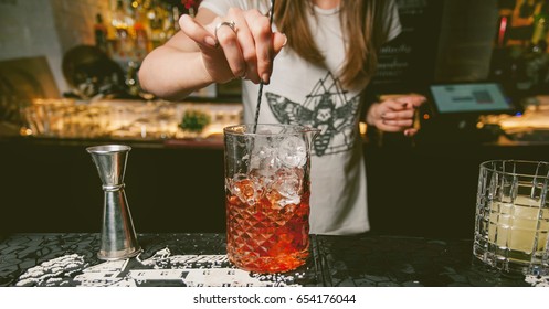 The girl bartender prepares a cocktail in the nightclub. Barmaid preparing cocktails in a bar for her clients - Bartender at work in a club. Bartender making alcoholic cocktail. photo vintage toning - Powered by Shutterstock