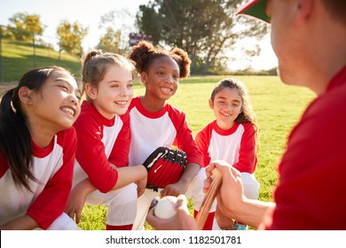 Girl Baseball Team In A Team Huddle With Coach, Listening