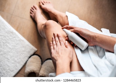 The girl in the bathroom puts anti-cellulite cream, serum on the legs and body. Body care concept. Top View
