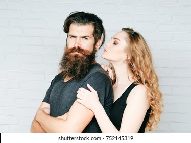 Girl And Bearded Hipster. Man With Beard And Woman With Long Blond Hair. Hipsterism, Subculture, Trend. Couple In Love Hug On White Brick Wall. Fashion, Beauty, Style Concept.