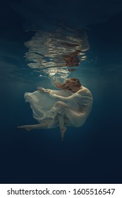 Girl in a beautiful dress swims underwater