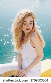 Girl With A Beautiful Face And A Calm Smile Looking Down Looking Over Her Shoulder Against The Background Of Sparkling Water