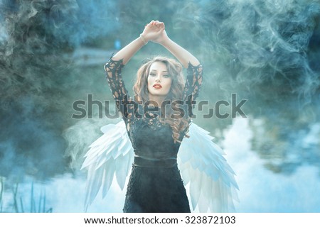 Girl with a beautiful face is to smoke. Behind her angel wings.