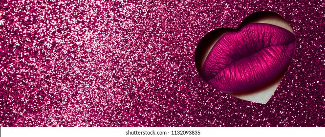 A girl with beautiful plump lips, painted pink lipstick with a metallic effect. Lips in a hole in the form of a heart of pink shiny paper.Fashion, beauty, make-up, cosmetics, beauty salon, style.