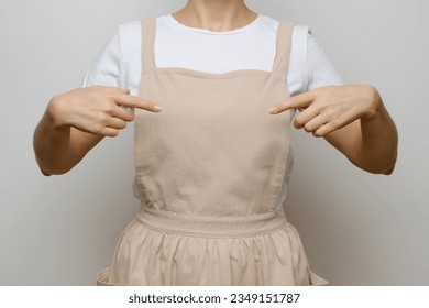 A girl in a beige apron points to her chest. Blank for design, place for text. Mockup.