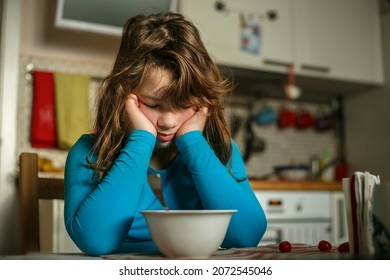 The girl bent over her breakfast plate in a disgruntled pose. Doesn't want to eat. - Powered by Shutterstock