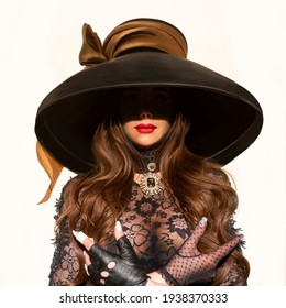 A girl in a big black hat, her face in shadow, only her lips vis