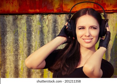 Girl with Big Headphones on Grunge Background - Beautiful young woman wearing headphones in an urban industrial decor 
